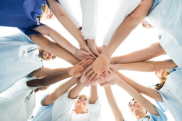 Multiethnic Medical Team Stacking Hands Directly below shot of multiethnic medical team stacking hands over white background stacked hands photos stock pictures, royalty-free photos & images