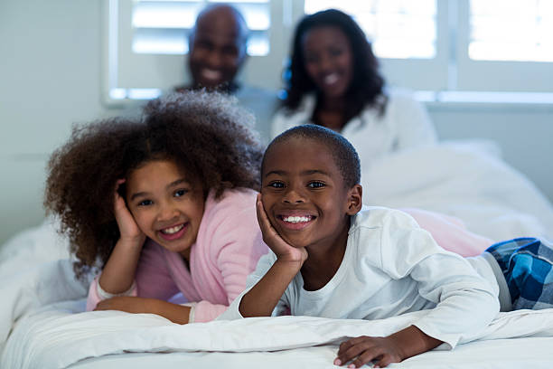 istock Children lying on bed with parents in background 618544208