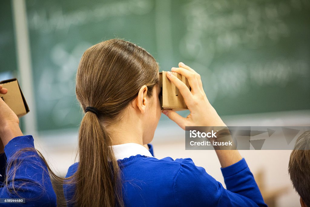 Students using virtual reality goggles Students using virtual reality cardboard goggles in the classroom. Black view. Virtual Reality Simulator Stock Photo