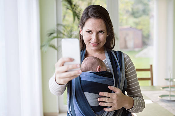 istock Young mother with her son in sling, taking selfie 618545394