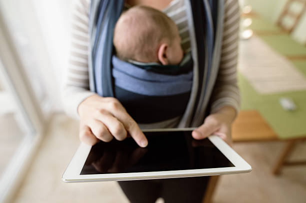 istock Unrecognizable mother with her son in sling, holding tablet 618545432