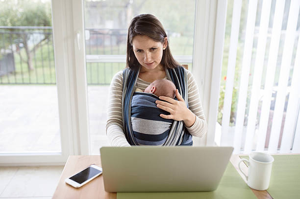 istock Young mother holding baby son, working on notebook 618545554