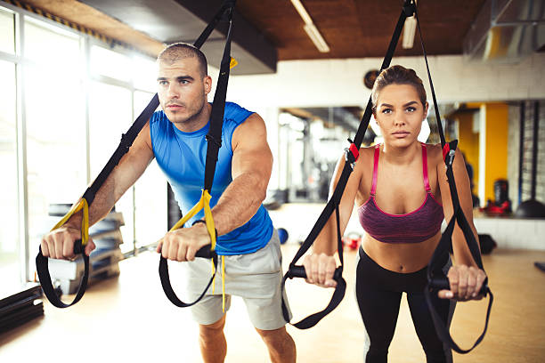 istock Couple doing arm exercises with suspension straps at gym. 618545828
