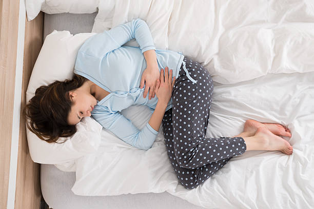 Woman Suffering From Stomach Ache Young Woman With Stomach Ache Lying On Bed pms stock pictures, royalty-free photos & images