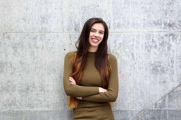 istock Happy young woman leaning against gray wall 618546266