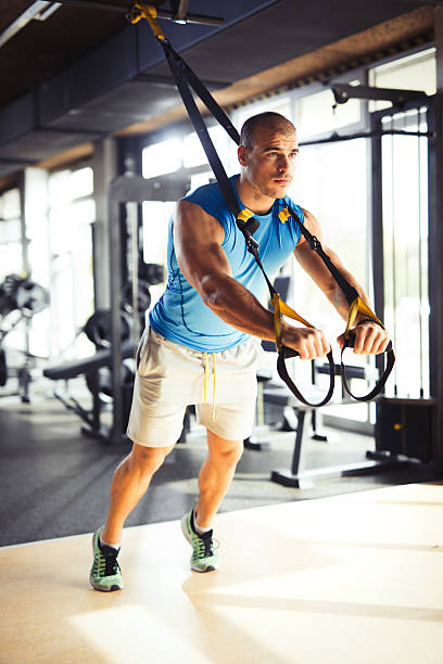 istock Man doing arm exercises with suspension straps at gym. 618546302