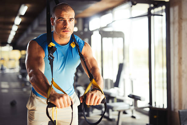 istock Man doing arm exercises with suspension straps at gym. 618546366