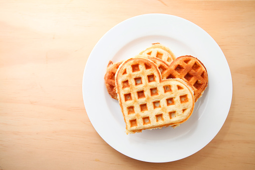 Heart shaped waffles over wooden table background