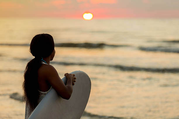 surfista adolescente vê o sol nascer sobre o oceano - surfing teenage girls friendship sunset - fotografias e filmes do acervo