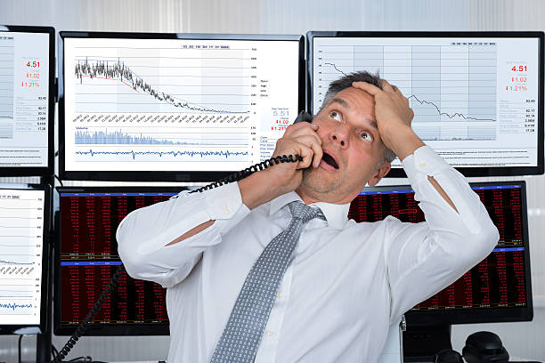 istock Sad Stock Trader With Hand On Head Using Telephone 618549160