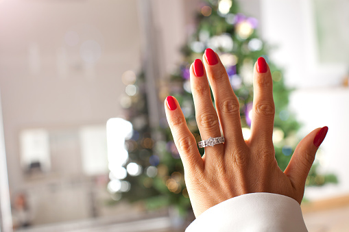 Diamond ring on a finger under the Christmas tree.