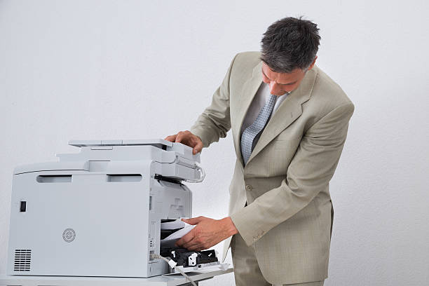 istock Businessman Removing Paper Stuck In Printer 618549460