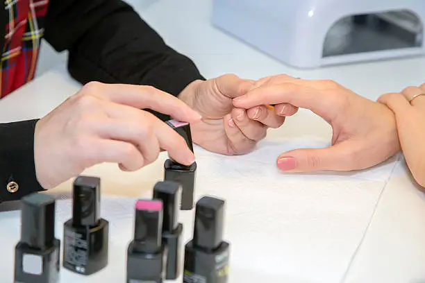 Manicurist doing manicure client painting nails with polish in salon
