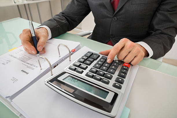 istock Close-up Of Businessman Calculating Invoice Using Calculator 618550124