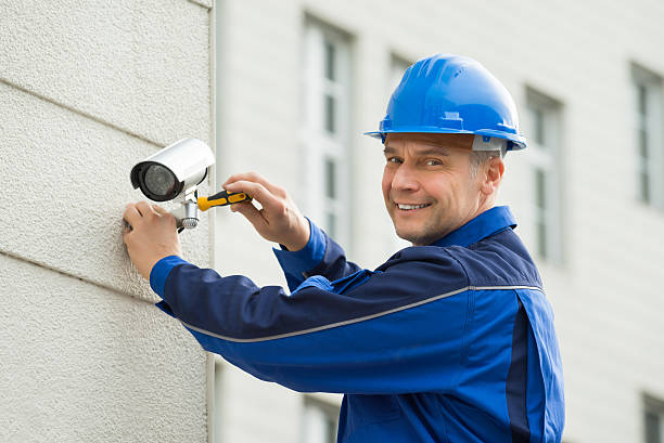 Mature Technician Installing Camera On Wall With Screwdriver Mature Male Technician Installing Camera On Wall With Screwdriver CCTV camera stock pictures, royalty-free photos & images