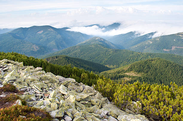 istock Stones against the hill covered with fluffy white clouds 618550632