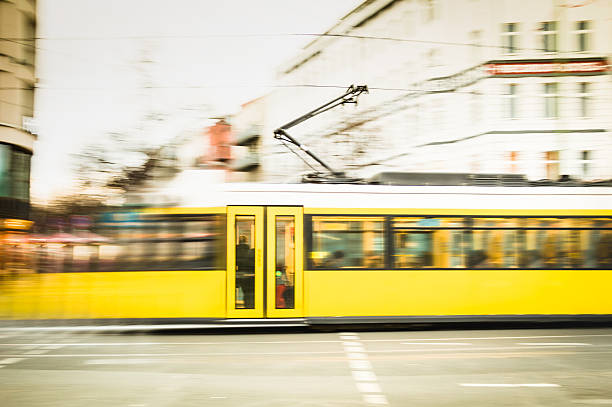 Blurred motion of defocused yellow tram on Berlin streets Blurred motion of defocused yellow tram on the streets of Berlin - Transport concept with public vehicle speeding at rush hour on city road - Warm vintage filter with blurry composition friedrichshain photos stock pictures, royalty-free photos & images