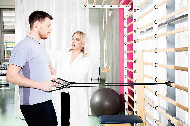 physiotherapist helps a patient to restore movement - fotografia de stock