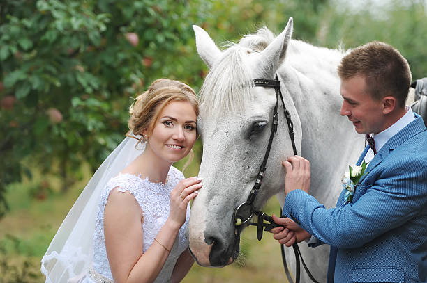 istock Bride and groom next to a beautiful thoroughbred horse 618608306