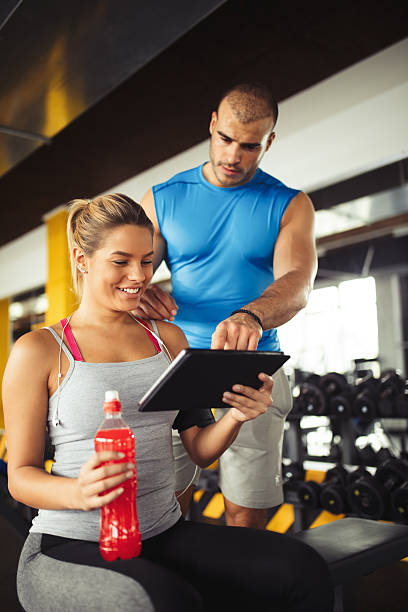 istock Young woman discussing workout plan with fitness instructor 618608332