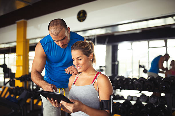 istock Young woman discussing workout plan with fitness instructor 618608502