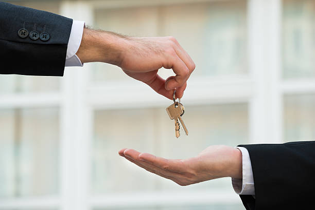 agent immobilier donnant des clés de maison à l’homme d’affaires - human hand key giving carrying photos et images de collection