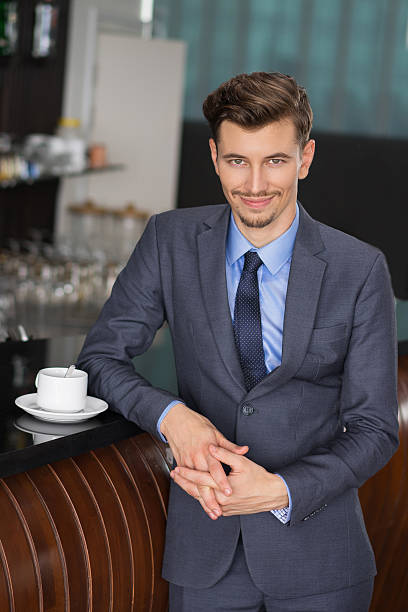 istock Content Businessman Leaning on Cafe Counter 618615098