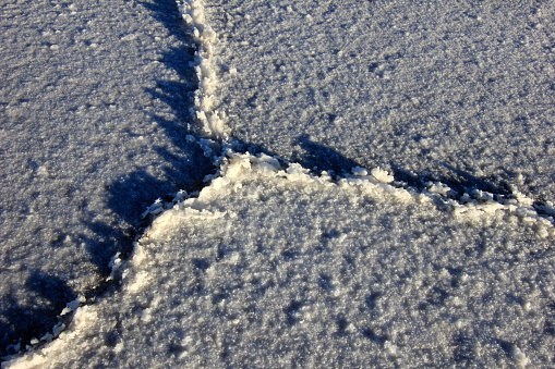 Spring ground covered with thawing snow. Melting ice on dry grass close up.