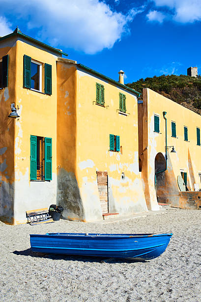Yellow houses and blue boat on Varigotti beach stock photo
