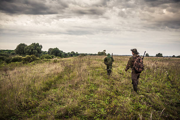 istock Hunters going through rural field with dramatic sky during hunting 618619970
