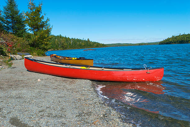 canoa roja en la orilla rocosa del lago moose bwca - canoeing canoe minnesota lake fotografías e imágenes de stock