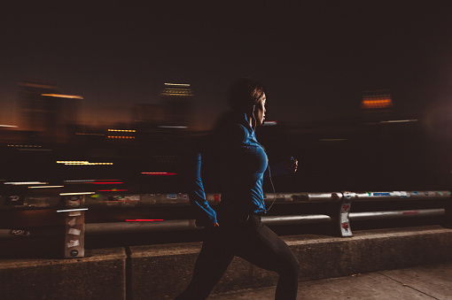 Young women running fast through the city at night.