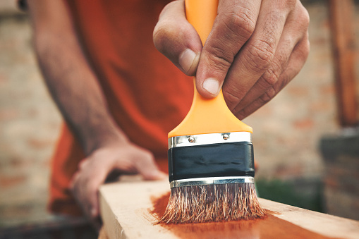 Outdoor portraits of young man cutting painting and repairing wooden boards. Shallow DOF. Developed from RAW; retouched with special care and attention; Small amount of grain added for best final impression. 16 bit Adobe RGB color profile.