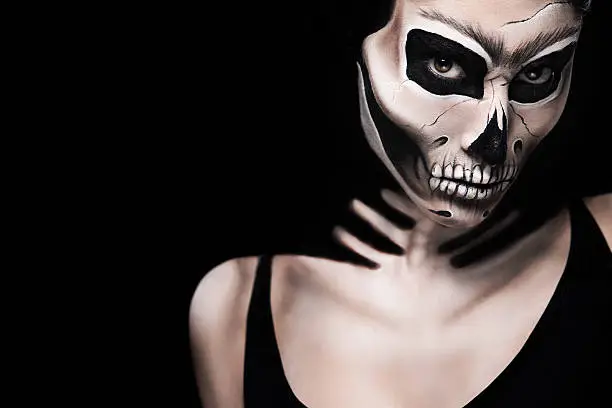 Woman in Halloween costume of Frida Kahlo on black background. Skeleton or skull makeup.
