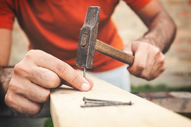 clous de marteau et mains en gros plan - home improvement hammer work tool nail photos et images de collection