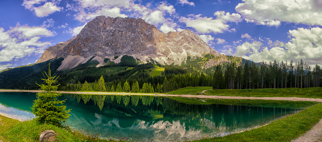 La blue clear lake near the mountain: Zugspitze, in Austria Europe. With a cloudy blue sky and a lot of trees.