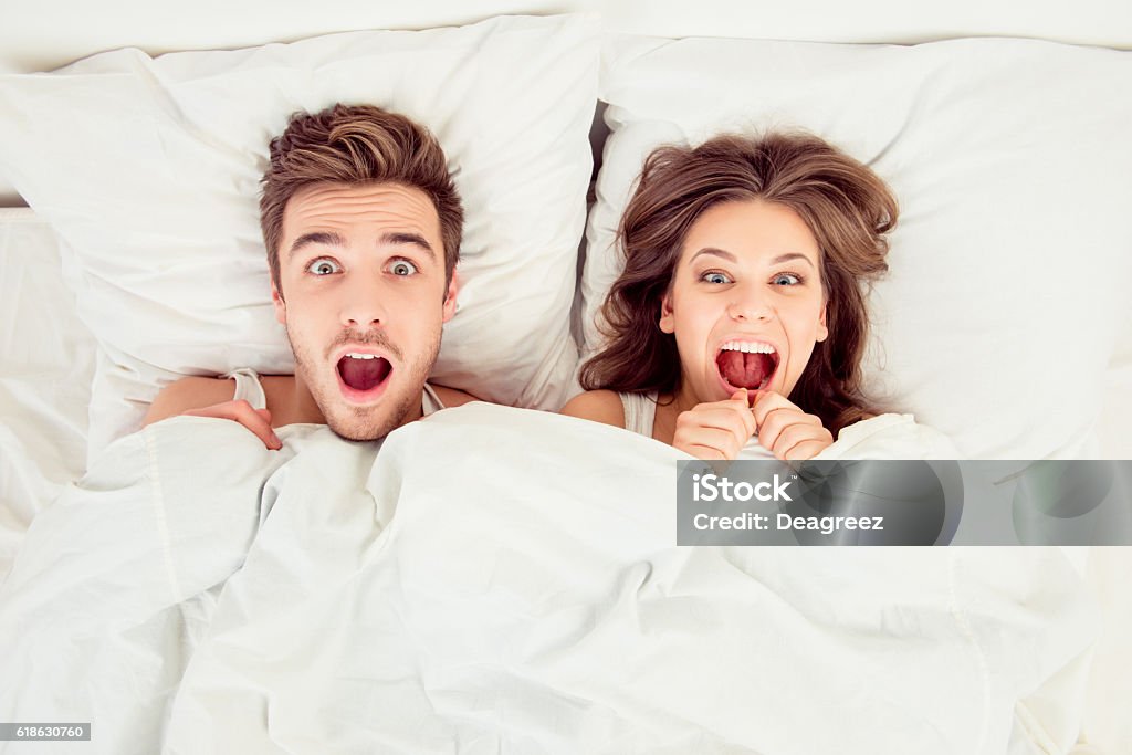 Surprised funny couple in love lying in the bed Sex and Reproduction Stock Photo