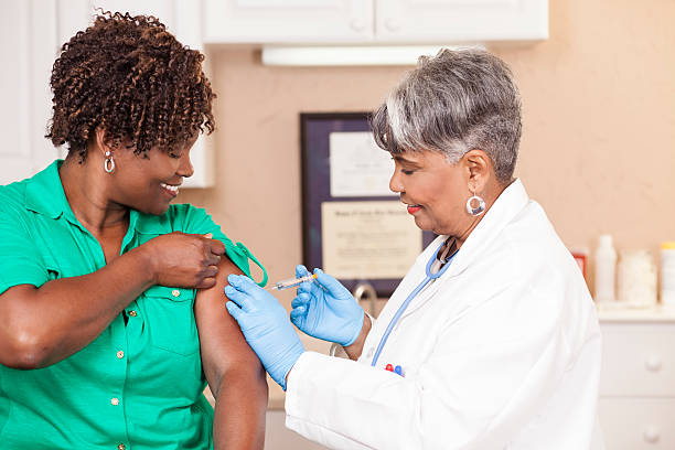 Doctor or nurse gives flu vaccine to patient at clinic. stock photo