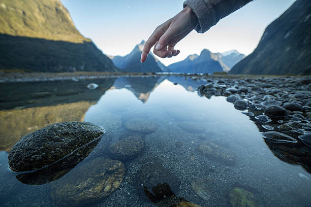 istock Finger touches surface of mountain lake 618636510