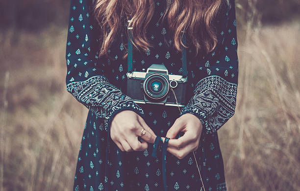 Pretty girl in dress with vintage camera in park