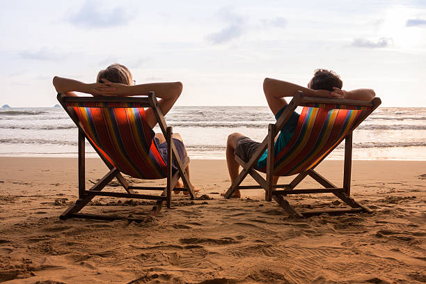 istock Couple in deck chairs at sea beach 618637356
