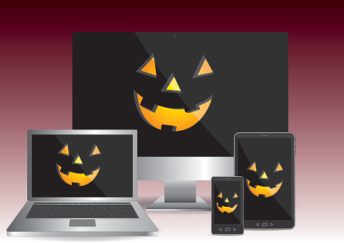 Personal computer, laptop, tablet and smartphone showing a scary pumpkin face in halloween