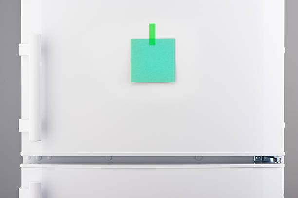 istock Blank green paper note attached by sticker on white refrigerator 618641924