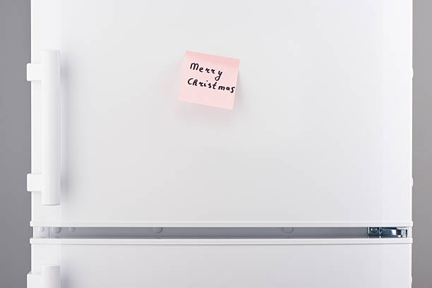 istock Merry Christmas note on pink sticky paper on white refrigerator 618641976