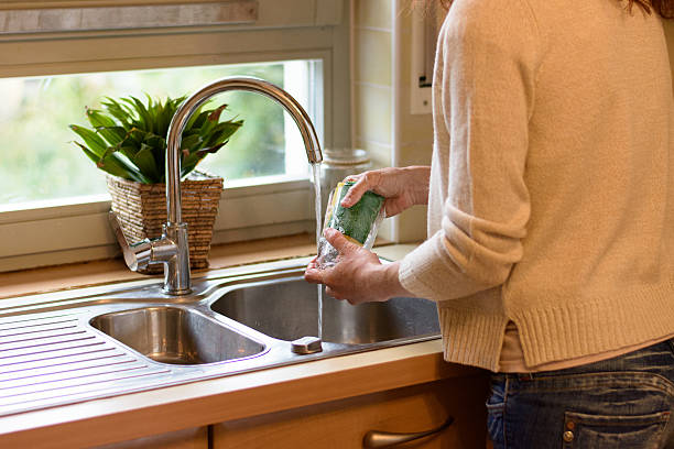 istock Woman washing a glass at the kitchen sink 618642498