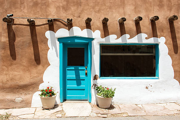 Santa Fe, USA - July 5, 2013: Santa Fe blue door on stucco wall with potted flowers and wooden roof beams (Vigas)