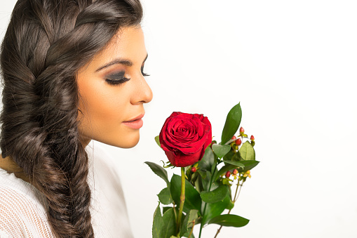 Beautiful young woman with long braided hair holding red rose