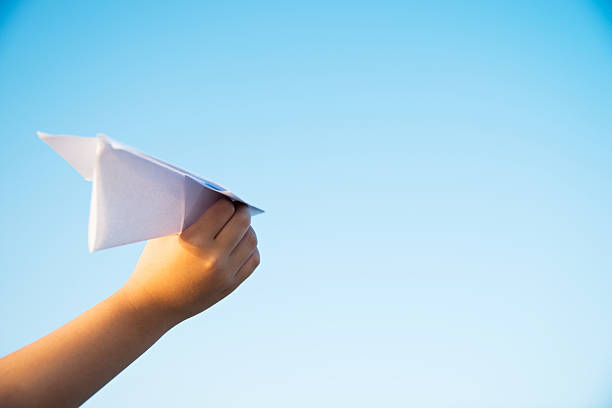istock Boy hand holding a paper plane with view of sky 618650278