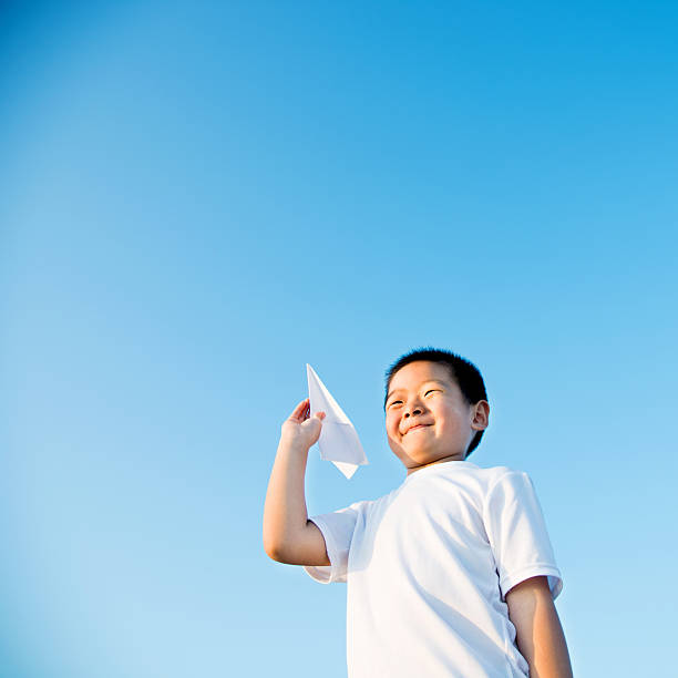 istock Boy hand holding a paper plane with view of sky 618650832