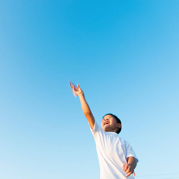 istock Boy hand holding a paper plane with view of sky 618650886